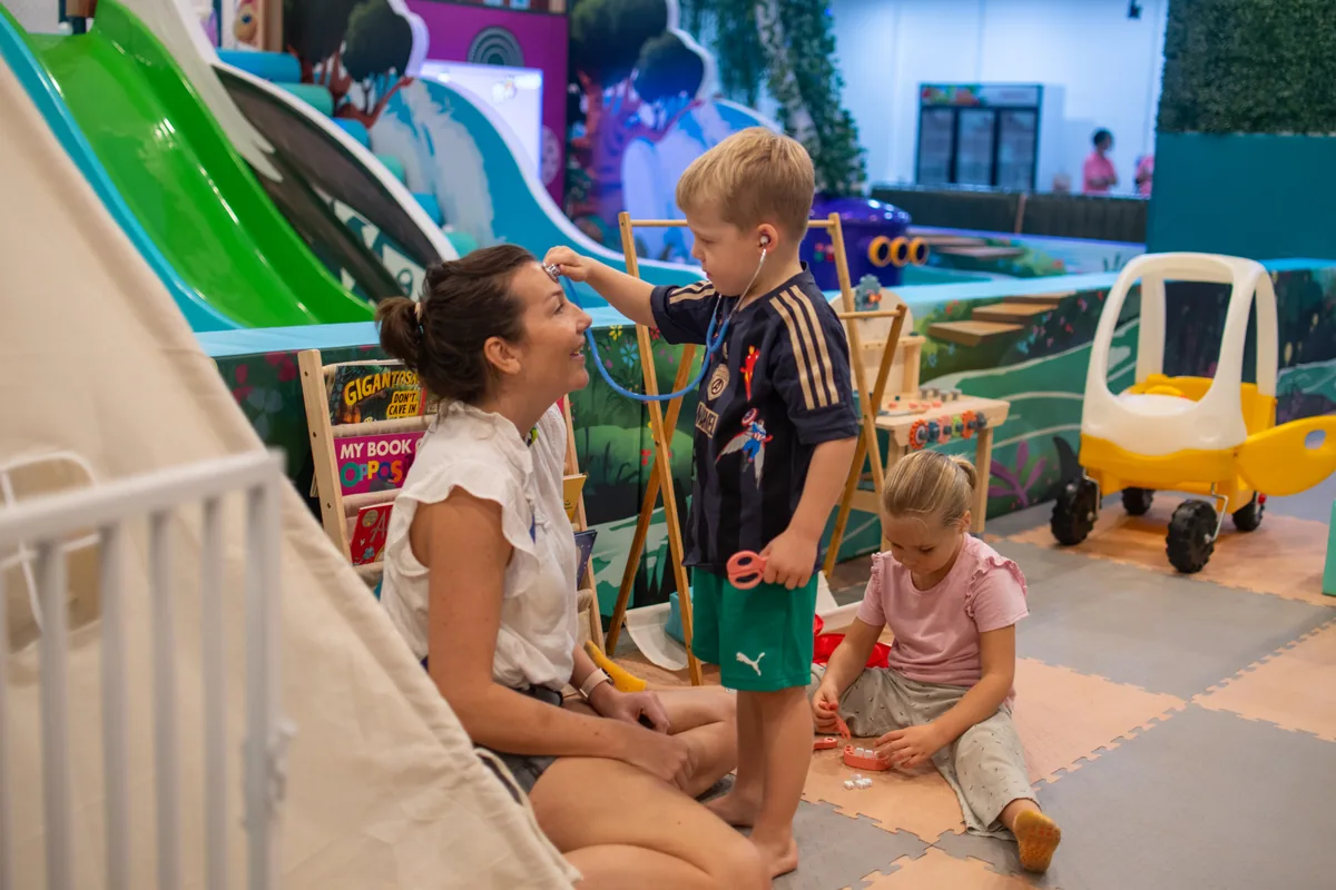 A parent and children enjoying role play together at Play Kingdoms